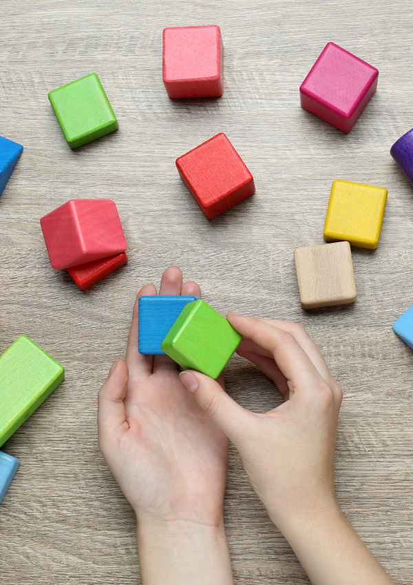 ABA therapy near me represented by hands using colorful wooden blocks during a structured learning activity